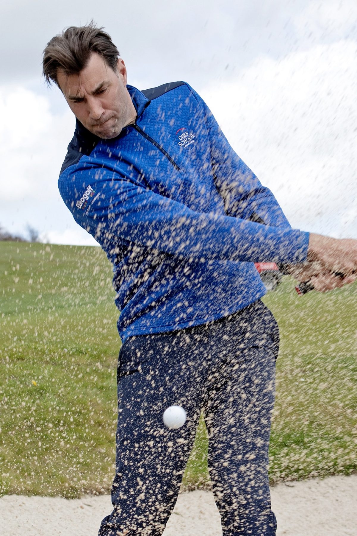 Leon Marks playing a bunker shot, sand spraying around the ball