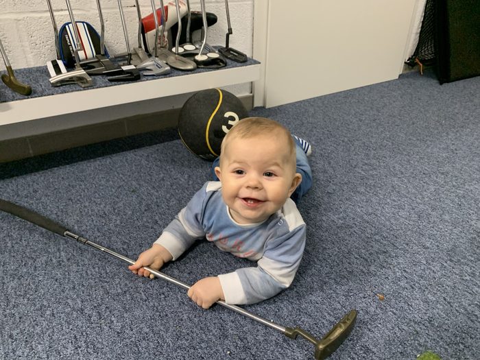 A baby holding a putter