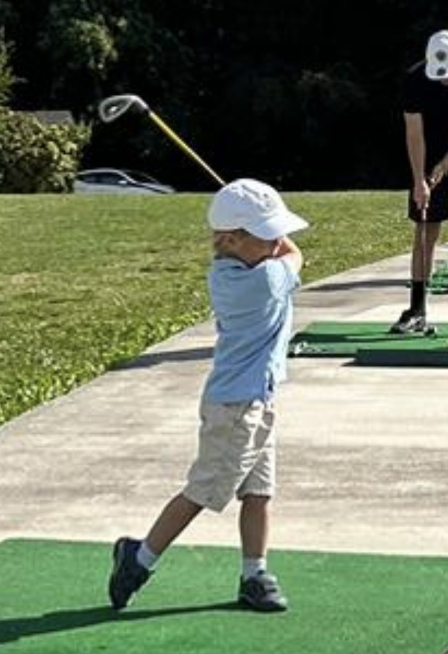 A young child swinging a golf club on the range