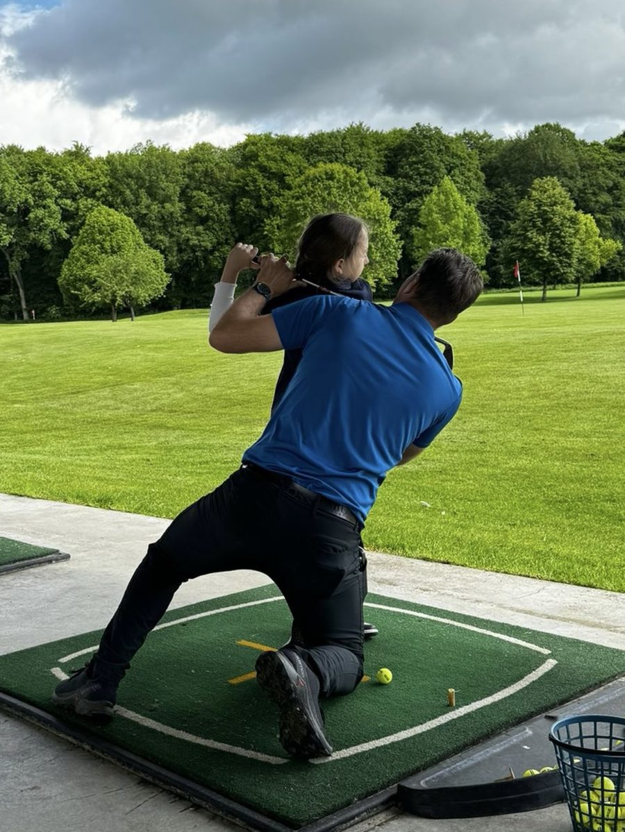 Coach working with a junior on the driving range